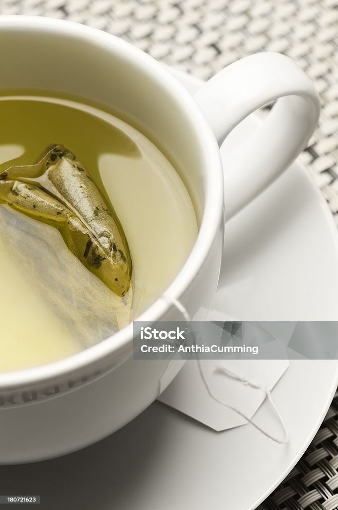Green tea and teabag in white cup and saucer Green Tea in a cup and saucer on a bamboo mat Teabag Stock Photo