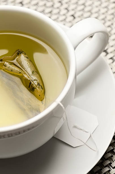 zielona herbata i torebka herbaty w biały filiżankę i spodek - green tea tea teabag green zdjęcia i obrazy z banku zdjęć