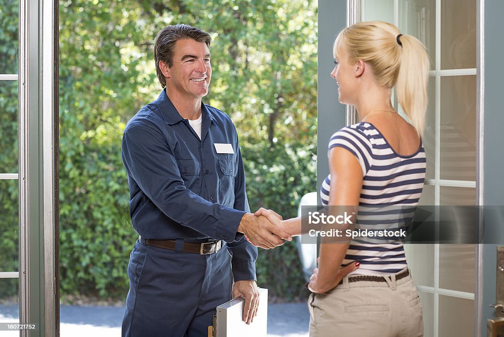 Consertador de uniforme cumprimentando dona de casa - Foto de stock de Eletricista royalty-free