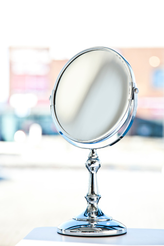 A round, table mirror with chrome articulated arm on a bathroom