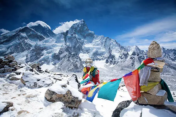 The colorful prayer flags on top of the mountain Kala Pattar. Behind the prayer flags can be seen Mount Everest and mount Nuptse. Photo is taken on the Himalayas Highs