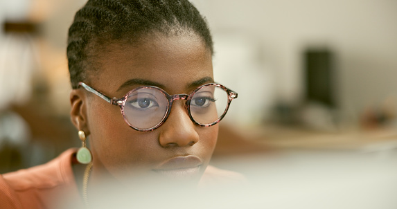 Research, focus or face of black woman with computer networking or searching online in office. Digital agency, glasses or African social media manager typing an email or planning in tech startup