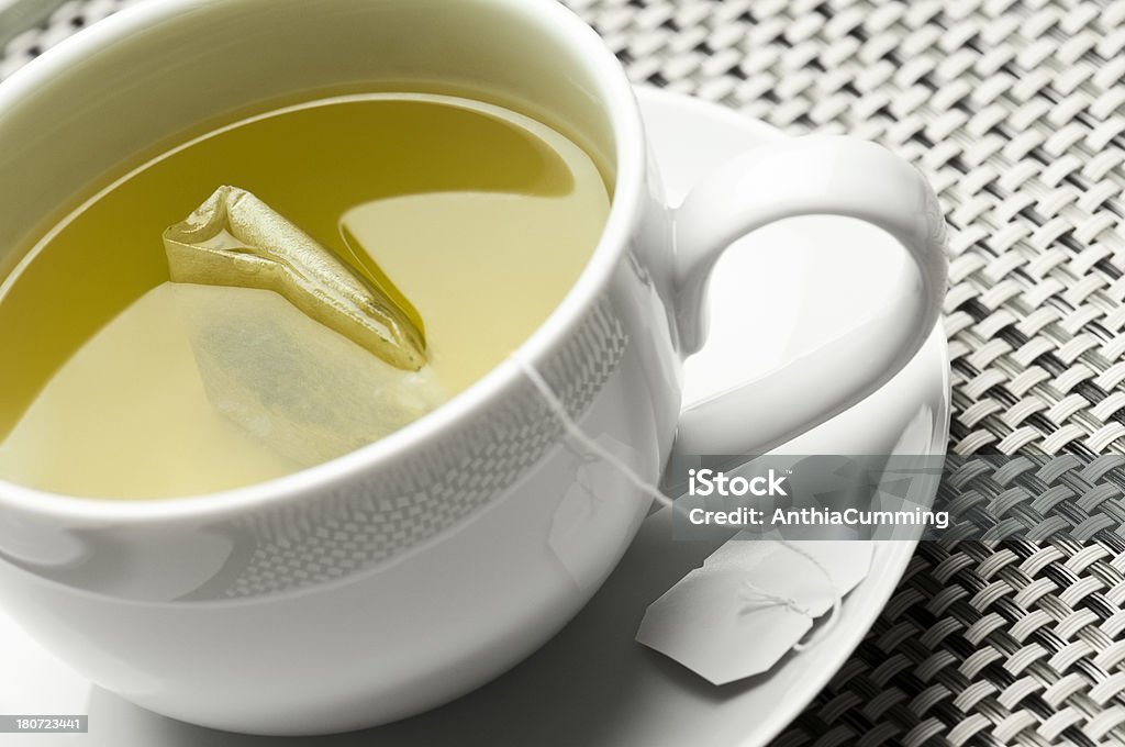 Green tea and teabag in white cup and saucer Green Tea in a cup and saucer on a bamboo mat Chai Stock Photo