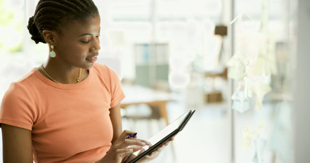 istock Black woman, tablet and schedule planning for strategy or creative ideas on glass board at office. African female person with technology for brainstorming, tasks or agenda in startup at workplace 1807241506