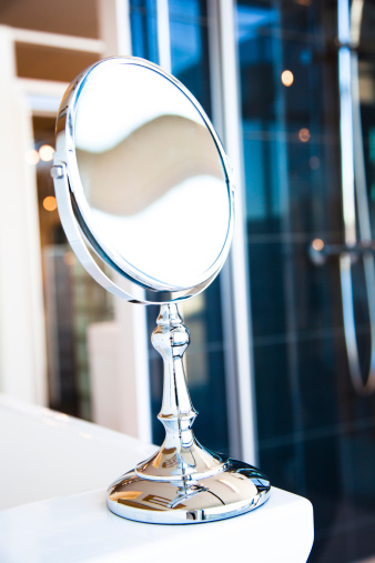 A round, table mirror with chrome articulated arm on a bathroom