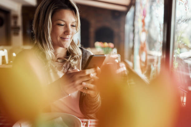 istock Smiling woman using cell phone in a restaurant. 1807244722