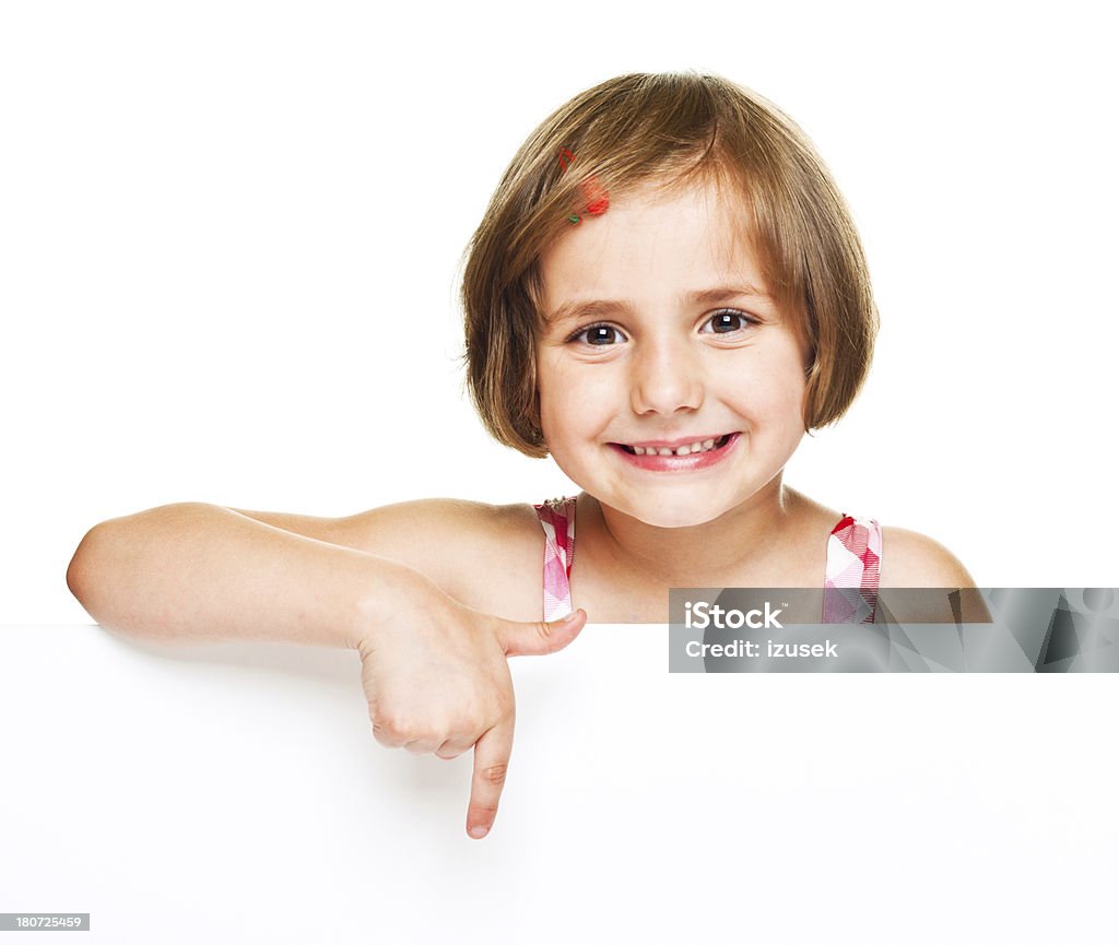 Cute Girl With A Blank White Board A cute little girl pointing at blank white board and smiling at the camera. Studio shot, isolated on white. Whiteboard - Visual Aid Stock Photo