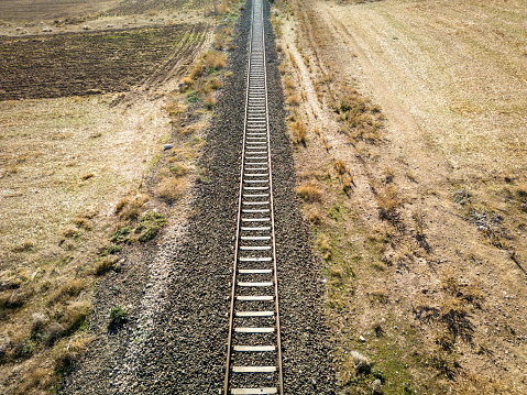 Top view of the train track passing through the arid land, taken with a drone
