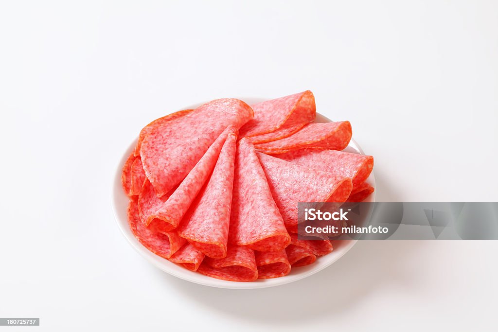 sliced salami stack of folded salami slices on a white plate Chopped Food Stock Photo
