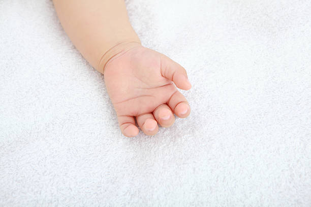 A detailed close-up of a newborn baby’s tiny hand emerging from a blue onesie, symbolizing the fragility and beauty of new life.