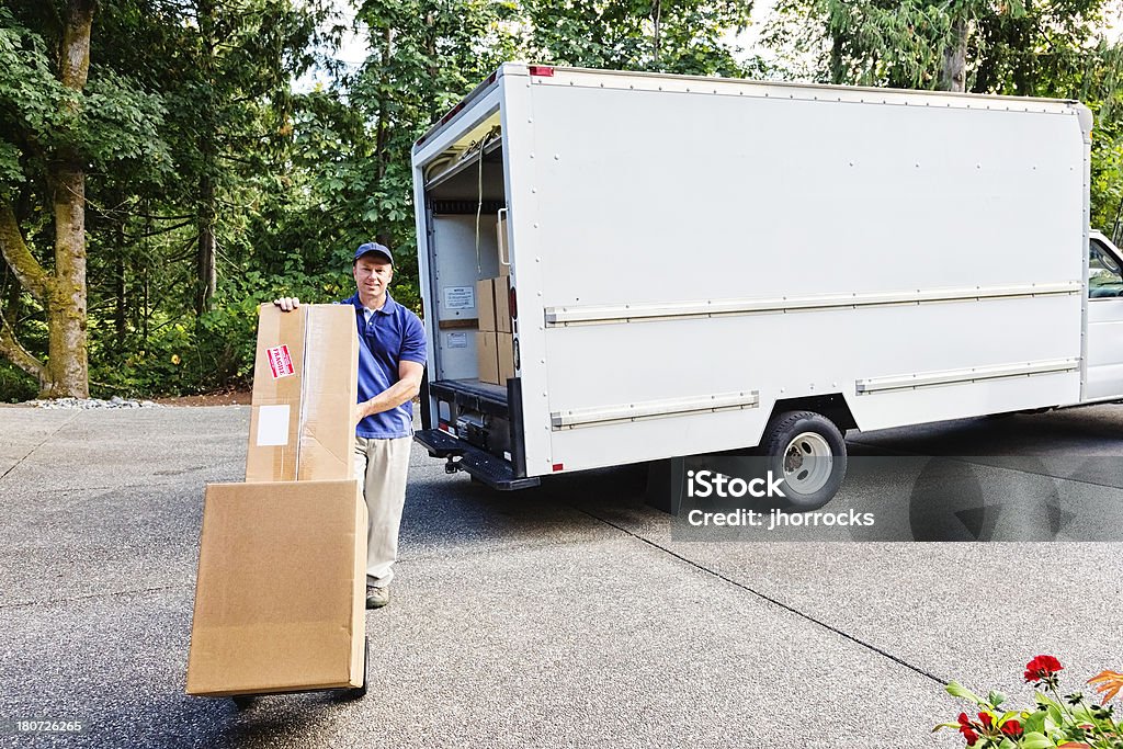 Delivery Man Photo of a delivery man with cardboard boxes on hand truck. Moving Van Stock Photo