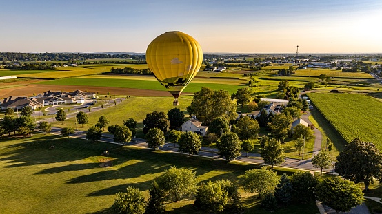 An aerial view of hot air balloons floating in the sky over a lush green field.