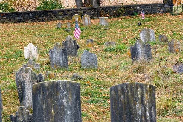 istock Cemetery, featuring a grassy field with several flags blowing in the wind. 1807264522