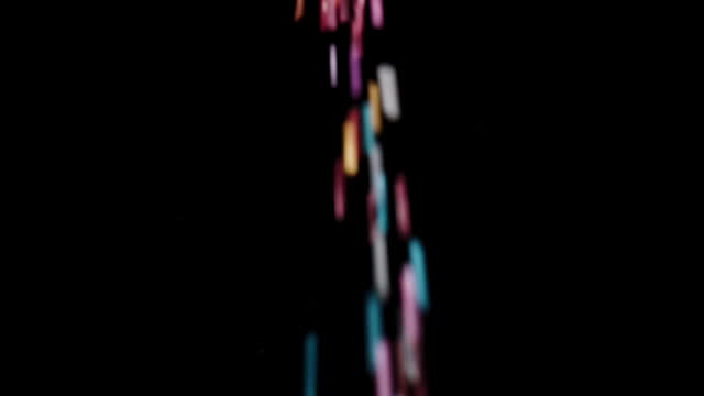 The Camera Captures a Close-Up and Follows the Multicolored Sugar Pouring Out of the Jar in Slow Motion Against a Black Background. Isolated.