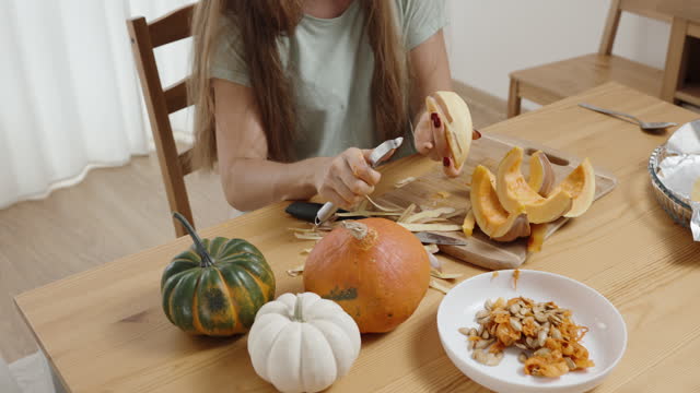Small Multicolored Pumpkins on the Table. The Woman Sliced One, Peeling and Cutting It for Baking.
