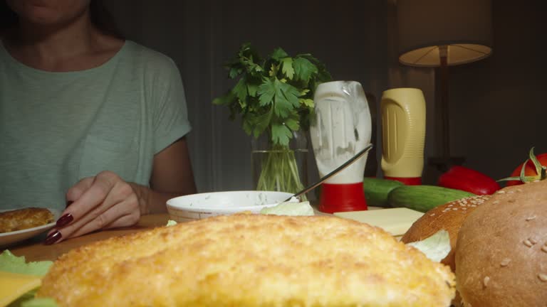 The Woman Is Preparing Homemade Burgers She Places Chicken Patties on Cheese in the Bun. Dolly slider extreme close-up.