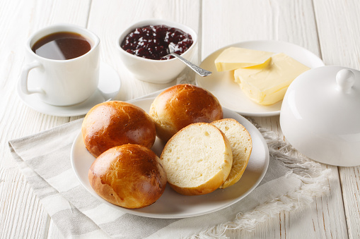 Norwegian Boller or Hveteboller Buns served with butter, jam and coffee closeup on the wooden table. Horizontal