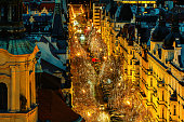 View of the street illuminated for Christmas holidays among typical historic buildings in Prague, Czechia.