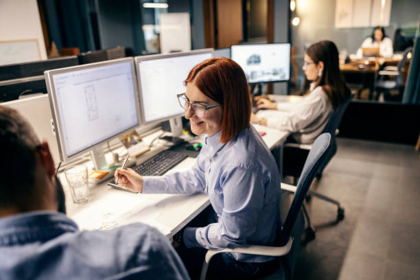 istock A happy architect is sitting at office and working on blueprints while smiling at colleague. 1807302837