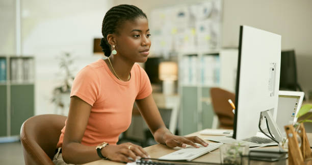 istock Technology, reading and young black woman in the office doing research for creative project. Desktop, career and professional African female designer working on computer in the modern workplace. 1807308698