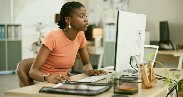 istock Computer, reading and young black woman in the office doing research for creative project. Technology, career and professional African female designer working on desktop in the modern workplace. 1807308699