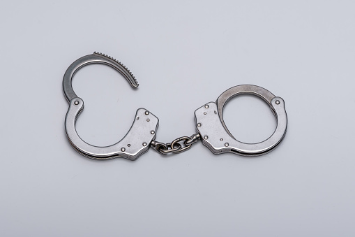 Steel handcuffs isolated on light background close up,