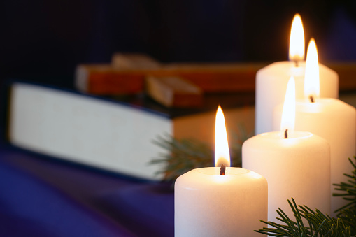 Four burning Advent candles with Bible and cross in background, religious symbol concept creative