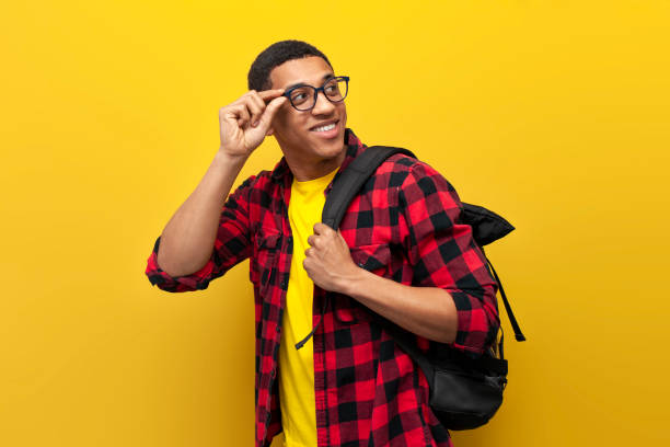 istock young guy african american student in glasses with backpack looks back on yellow isolated background 1807317285