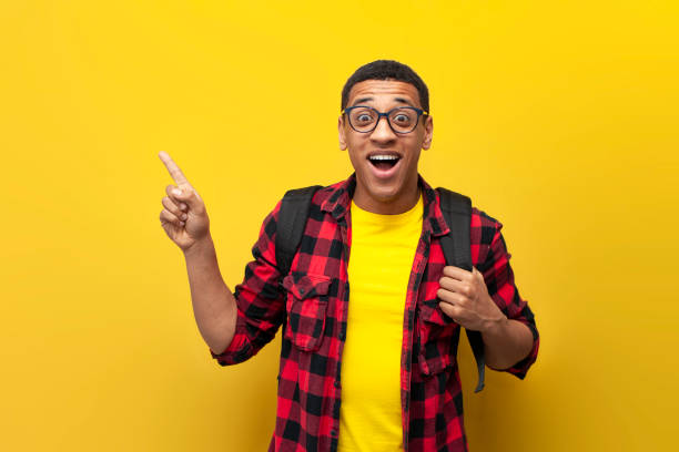 istock young guy african american student in glasses with backpack shows on the copy space on yellow isolated background 1807317811