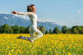 happy mature woman jumping in flower meadow