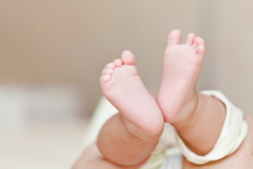 Mother's hands holding newborn's feet