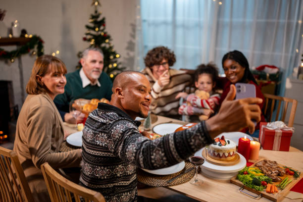 istock Multi-ethnic family using mobile phone video call online to relative. Attractive diverse group of people having dinner eating food to celebrate holiday Thanksgiving, X-mas eve on dining table at home. 1807359157