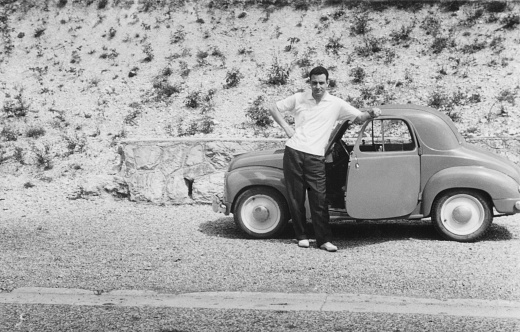Young man and vintage car Fiat 500 Topolino in a road. 1952.