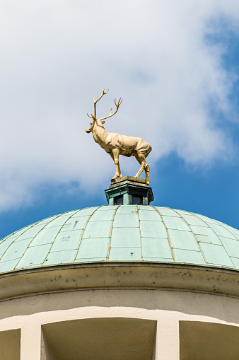 Golden deer on the roof in Stuttgart, Germany.Representative dome with golden deer, the emblem of Württemberg. The building is right next to the new castle on the northern flank of the castle square of Stuttgart, Germany. Copy space on the sky in the background.