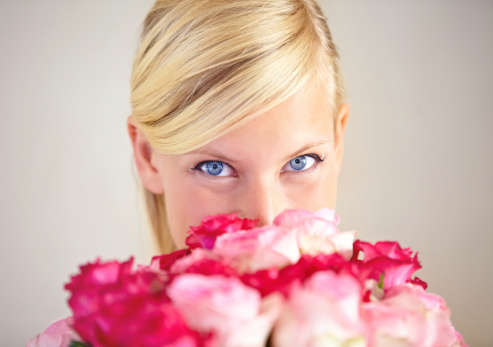 Portrait of a beautiful young woman sniffing a bouquet of roses