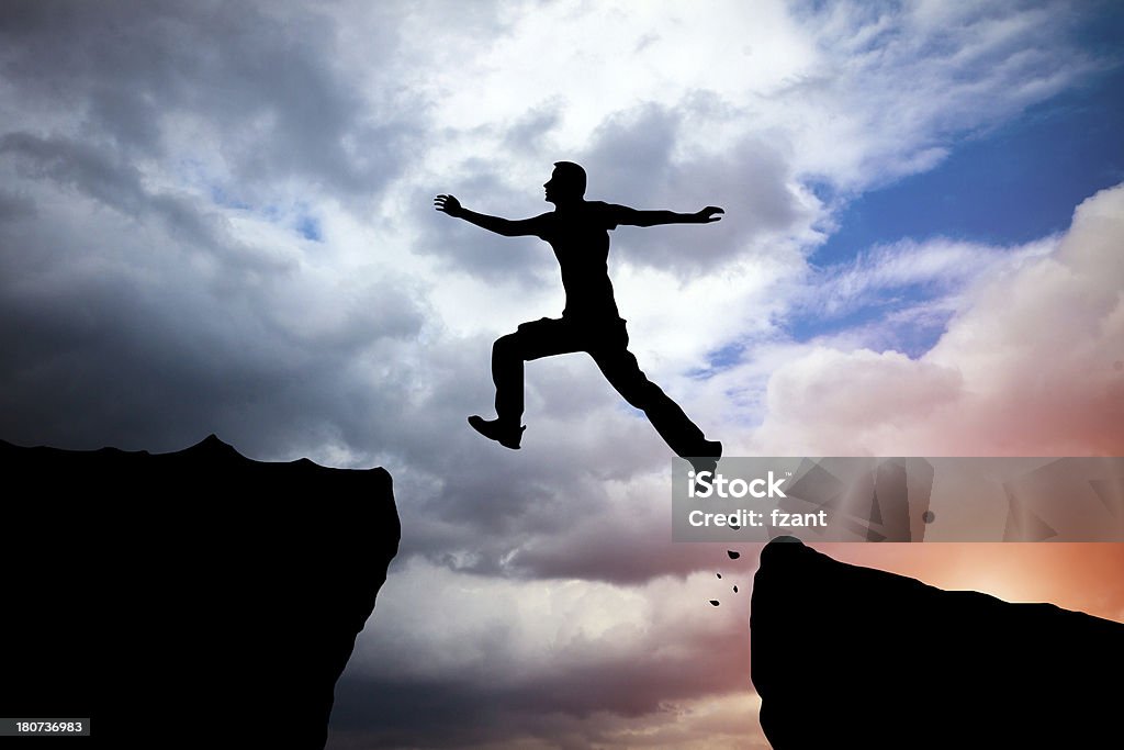 jumping Silhouette of hiking man jumping over the mountains Activity Stock Photo