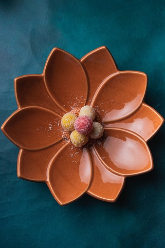 A close-up of a porcelain flower-shaped bowl resting atop a pale turquoise tablecloth