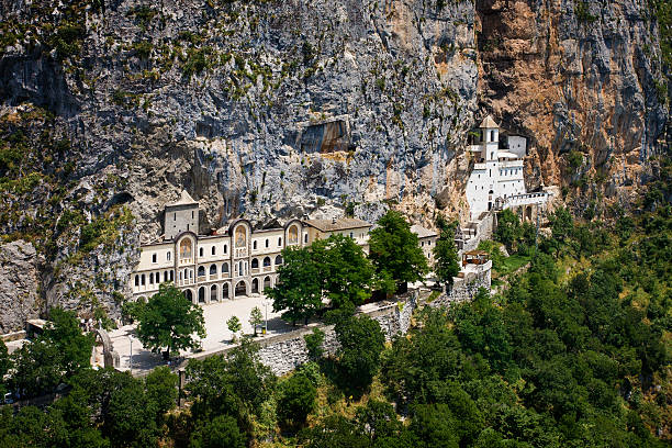 Monastery of Ostrog, Montenegro (aerial view) "Aerial photo of ancient Orthodox monastery carved in a mountain cliff, 900m above the sea level. The Monastery of Ostrog (Manastir Ostrog) is one of the major pilgrimage sites in the Balkans and one of the most visited Christian destinations in the World, visited by more than a hundred thousand pilgrims and travellers of all religions every year. The Church is dedicated to Saint Basil of Ostrog (Sveti Vasilije OstroA!ki). Photo was taken from the helicopter.Similar:" monastery stock pictures, royalty-free photos & images