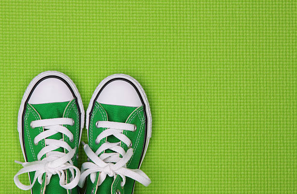 Bright green children's canvas sneakers on a green textured background.