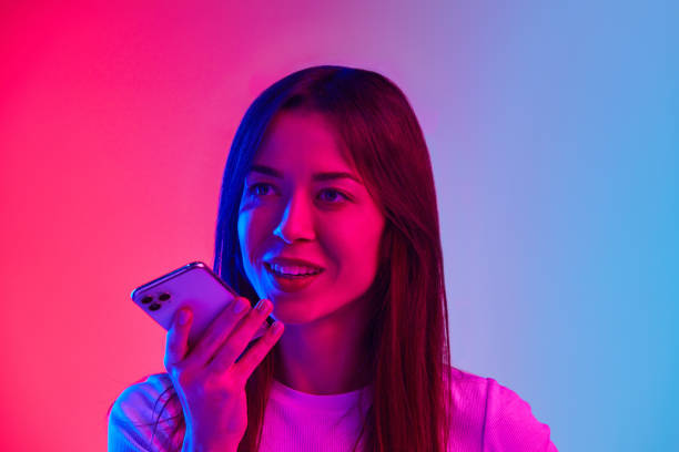 istock Young woman talking on mobile phone against gradient pink blue studio background in neon light. Communication 1807390791