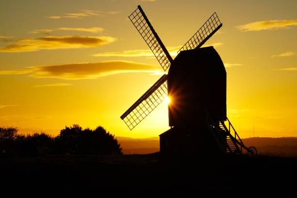 An isolated windmill with a sunset backdrop sits atop a hill in Brill, England