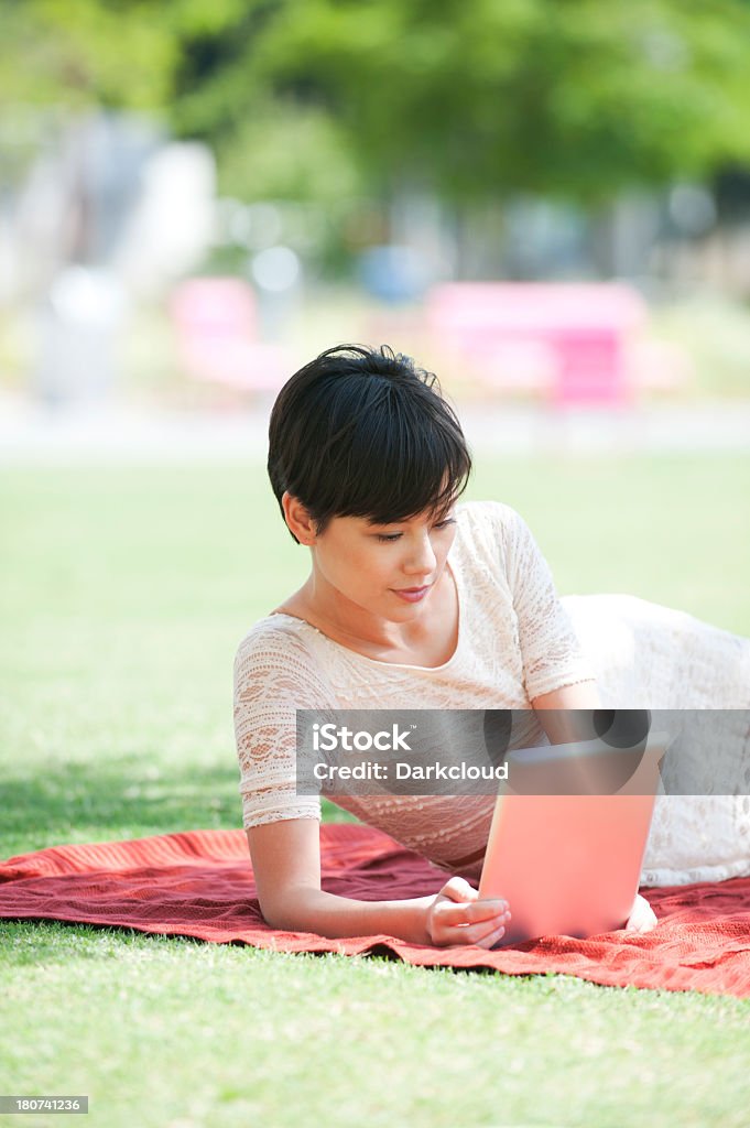 Woman with digital tablet in the park A young woman using a digital tablet in the park. Adult Stock Photo