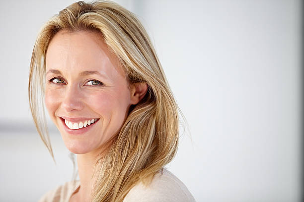 Her smile could brighten any room! Cropped portrait of an attractive woman smiling against a white background older blonde woman stock pictures, royalty-free photos & images