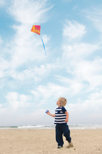 A boy flying a kite on the beach.