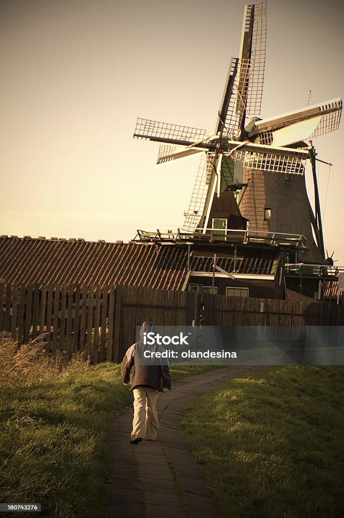 Little Don Chisciotte Young boy walking against a windmill. Boys Stock Photo