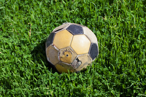 Close-up of old soccer ball on green grass