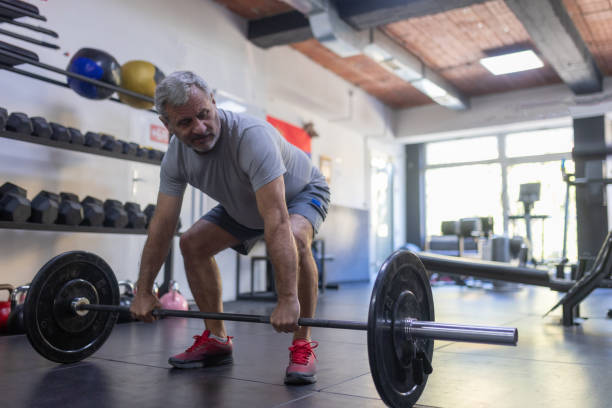 istock An elderly man is working out in the gym, lifting weights 1807447779