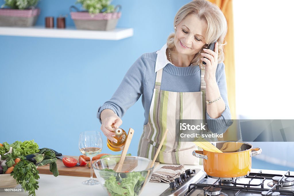 Senior woman cooking. Beautiful senior woman cooking in kitchen.See more KITCHEN and LIFESTYLE images with this SENIOR WOMAN. For lightbox click any image below. 50-59 Years Stock Photo