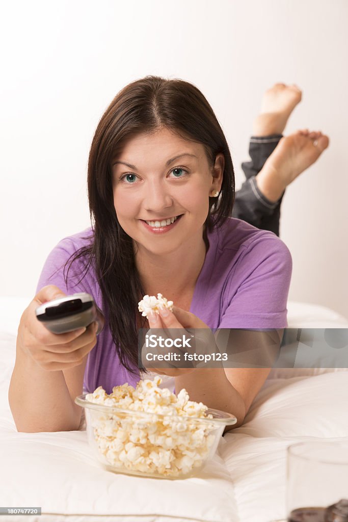 Technologia: Kobieta oglądania telewizji. Zimny napój. Popcorn. Zdalny. - Zbiór zdjęć royalty-free (20-24 lata)