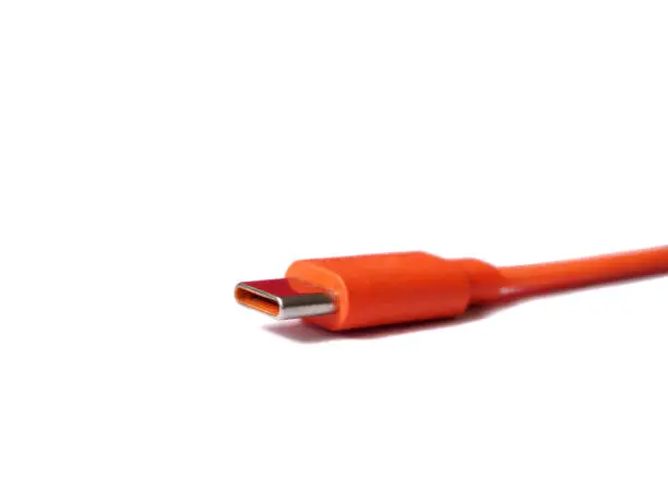 C type Usb connector isolated on the white. Usb cord in orange.  Cable for data transmisson or charge. Focused on connector.
